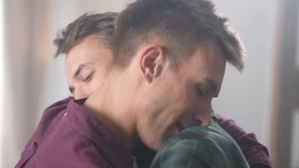 Autentyczne zbliżenie ujęcia kochającej gejowskiej pary delikatnie się przytulającej, a potem patrzącej w oczy z uśmiechem. Szczęśliwych związków par tej samej płci. Wysokiej jakości materiał 4K - Materiał filmowy, wideo