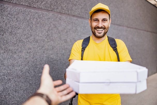 Courier delivering pizza to man with thermal backpack. Takeaway food delivery concept. - Photo, Image