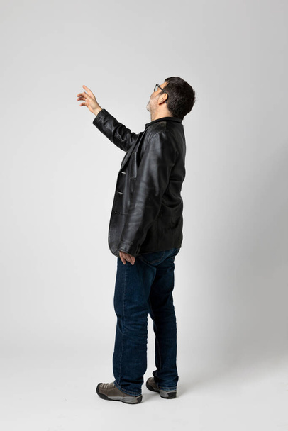Isolated man on white background is standing with his back turned and pointing to an indefinite point above with his finger. Copy space - Foto, afbeelding