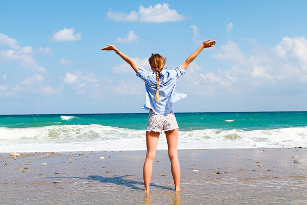 the concept of freedom and independence - a happy girl stands on a sandy beach and - Foto, imagen