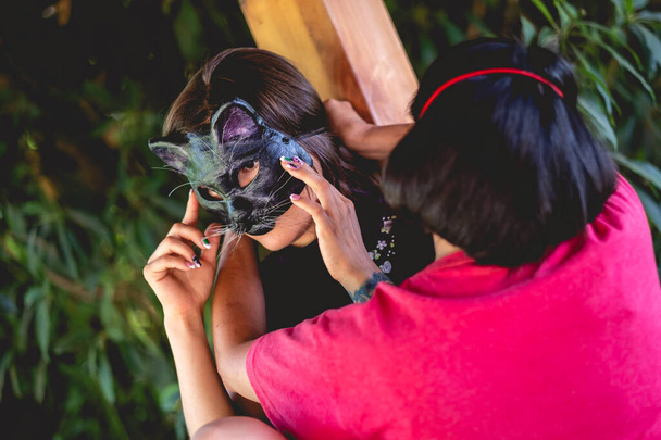 Татуированная сексуальная молодая брюнетка в синем китайском платье с кошачьей маской, которую готовят в деревянном павильоне, окруженном джунглями - Фото, изображение