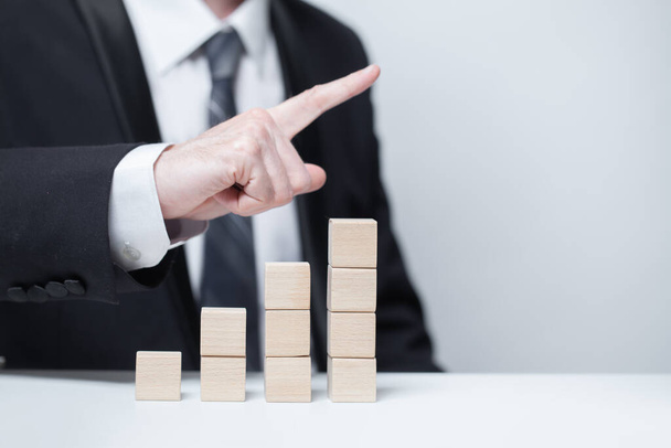 Wooden cubes, business growth success income concept, businessman pointing up - Foto, imagen