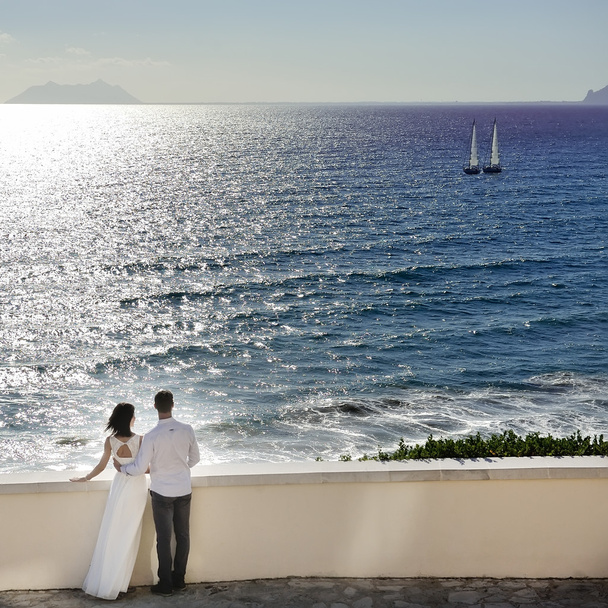 романтическая пара смотрит на море в день свадьбы в Италии
 - Фото, изображение