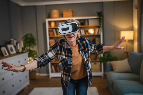 One woman mature senior caucasian female at home enjoy virtual reality VR headset - Фото, изображение