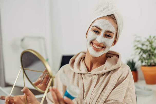 Portrait of a happy woman with a facial mask and a towel on her head - Photo, image