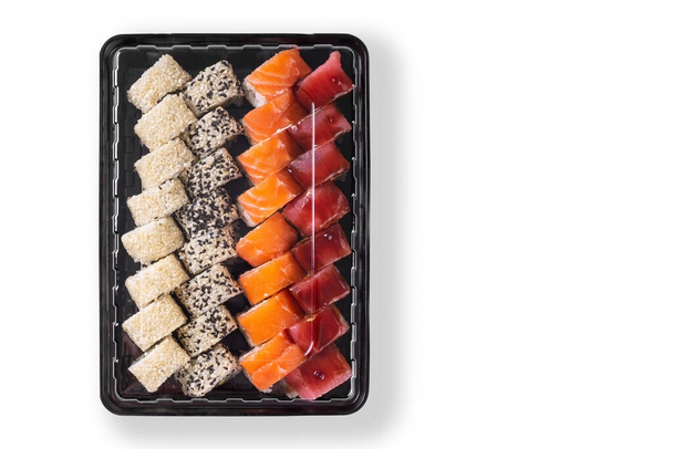 Sushi-Set mit Wasabi, Ingwer und Sojasauce, serviert in Plastikbox zum Mitnehmen, to go. Sortiert aus japanischem Sushi mit Thunfisch, Lachs, Sesam isoliert auf weißem Hintergrund. Draufsicht, flache Lage - Foto, Bild