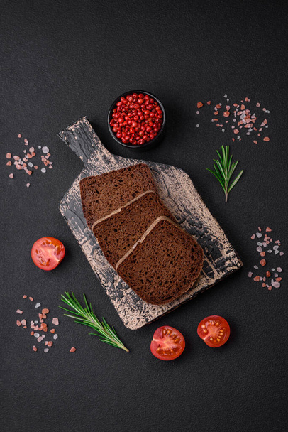 Pão fresco crocante com grãos e sementes sobre fundo de concreto escuro - Foto, Imagem