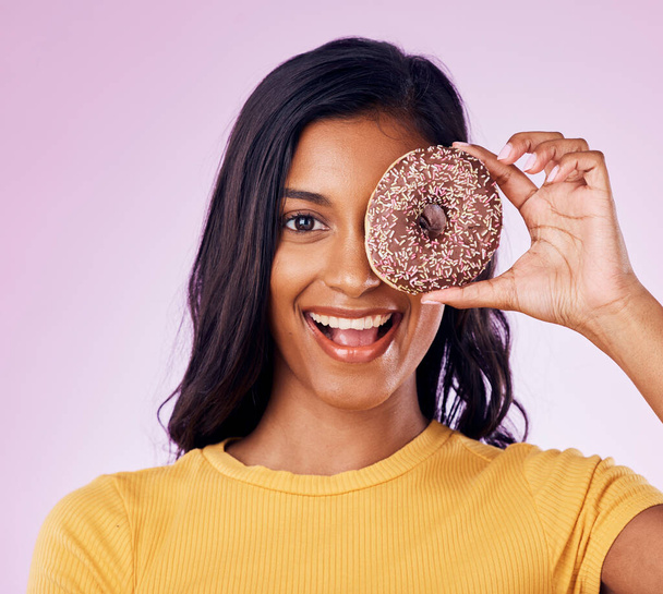 Donut, cover with portrait of woman in studio for diet, snack and happiness. Sugar, food and smile with female hiding and isolated on pink background for nutrition, playful and craving mockup. - Photo, Image