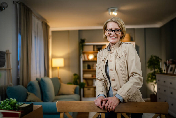 Portrait of one mature blonde caucasian woman with eyeglasses at home happy smile looking to the camera confident wear shirt copy space - Valokuva, kuva