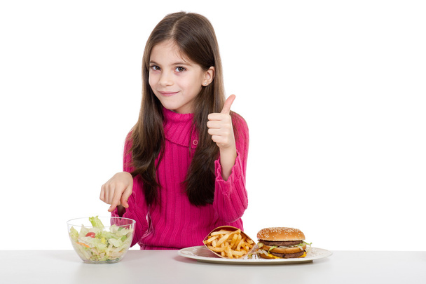Little girl with healthy and unhealthy food - Фото, изображение