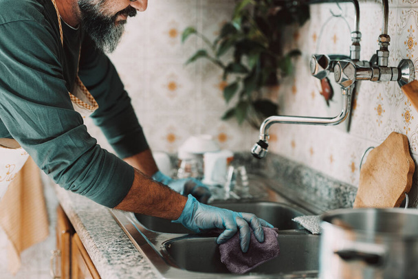 Close up of man at home cleaning the kitchen after cooking and washing the dishes. Alone male people lifestyle. Husband doing housework. Hygiene. Keeping home clean. Feminine work done by male indoor - Photo, Image