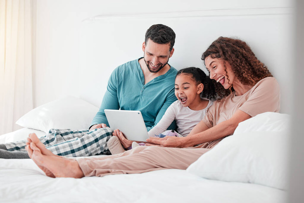 Mom, dad and child on bed with tablet, watching movies, streaming service for child development. Interracial family in bedroom bonding with happy online movie, man and woman with girl and happiness - Fotoğraf, Görsel