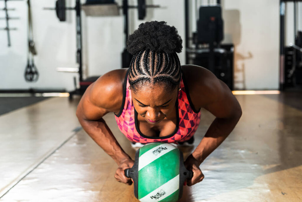 Mujer musculosa haciendo flexiones en el gimnasio. Determinación y enfoque. - Foto, Imagen