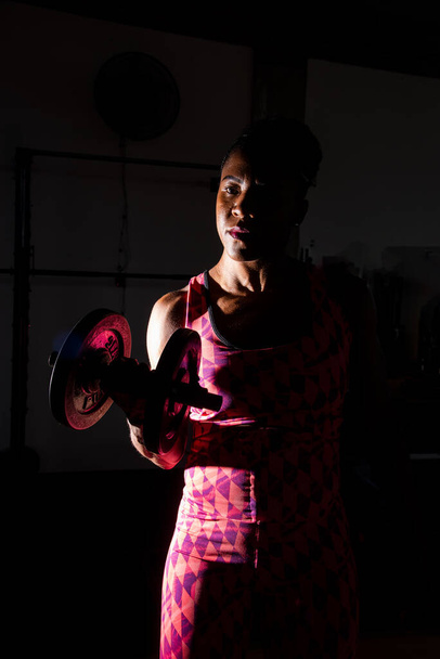 Dramatisches Porträt einer Fitness-Frau, die Übungen für die Armmuskulatur macht. Fitnesstraining. - Foto, Bild