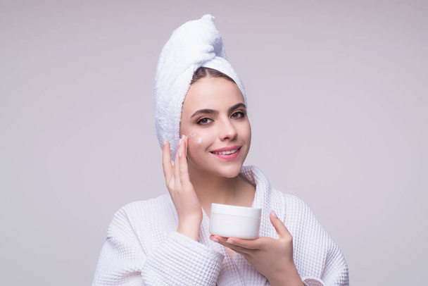 Beauty portrait of a beautiful woman applying face cream. Woman applying moisturizing skincare cream, lotion or mask for skin lifting and anti-aging effect, studio background - Foto, Bild