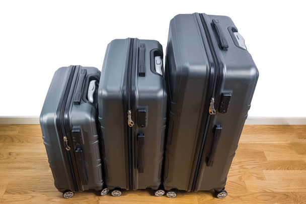 Вид крупным планом на три разных размера чемоданов, стоящих на паркетном полу в номере. Швеция. - Фото, изображение