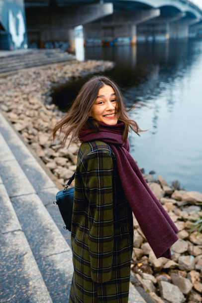 Young brunette woman smiling while walking outdoors. - Fotó, kép