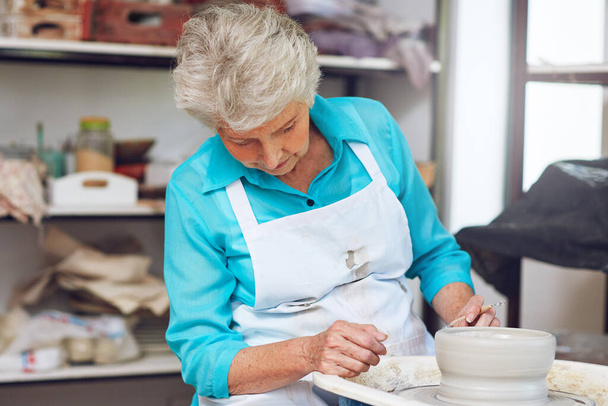 Creare il suo vaso di argilla con precisione e perfezione. una donna anziana che fa una pentola di ceramica in un laboratorio - Foto, immagini