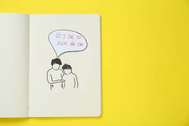 Card with phrase It`s Ok to Not Be Ok, drawing of mother and her son in notebook on yellow background, top view. Space for text - Photo, image