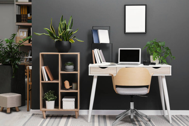 Workplace with laptop, stationery on desk and chair in home office - Фото, изображение