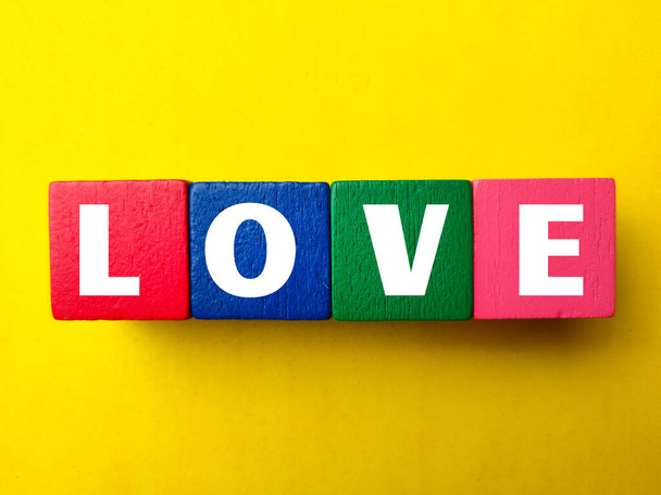 Wooden block with the word LOVE on a yellow background - Photo, Image