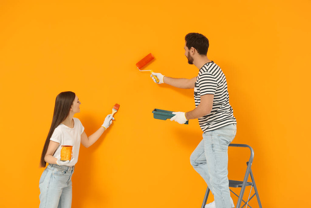 Designers painting orange wall with roller and brush - Fotoğraf, Görsel