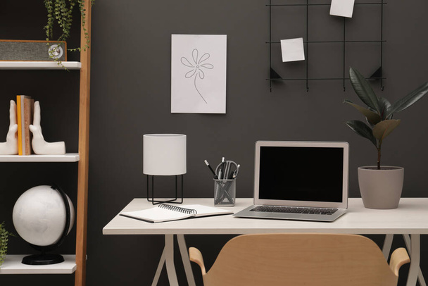 Cozy workplace with laptop and stationery on desk at home - Foto, Imagen