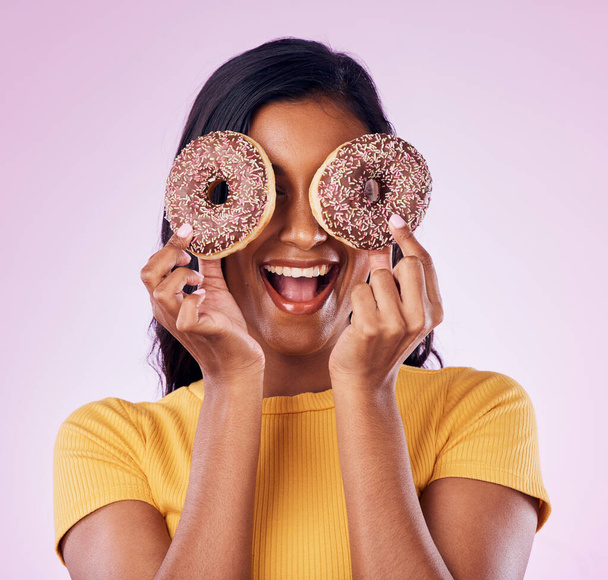 Donut, dessert and cover with woman in studio for diet, snack and happiness. Sugar, food and smile with female hiding and isolated on pink background for nutrition, playful and craving mockup. - Photo, Image