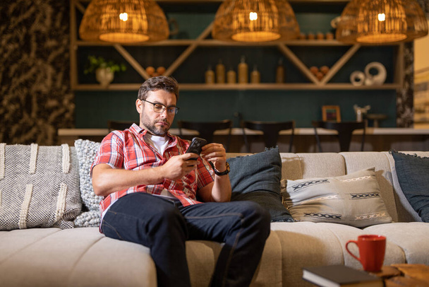Portrait of a cheerful man with smart phone at home. Guy using phone at home. Middle eastern mature man using phone for online payment. Man using cellphone. Guy using smart phone and mobile app - Fotoğraf, Görsel