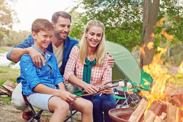 Het perfecte vuur voor het roosteren van marshmallows. een gezin van drie kampeerders in het bos - Foto, afbeelding