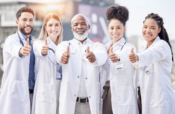 Portrait, collaboration and thumbs up with a team of doctors standing outside of a hospital together. Teamwork, thank you or motivation with a team of professional healthcare workers feeling positive. - Fotoğraf, Görsel