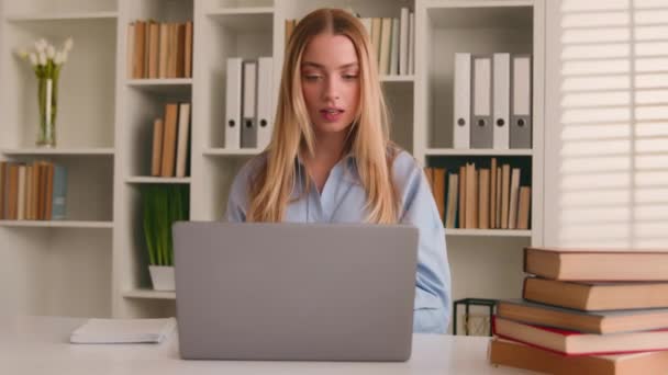 Valkoihoinen onnellinen naispuolinen opiskelija tyttö kotona kirjastossa opiskelee verkossa kirjoja kannettavan tietokoneen etäopetuksen kirjallisesti kotitehtäviä verkko-oppimista. Nainen liikenainen yritystutkimus tietokoneella kirjoittaa ideoita - Materiaali, video