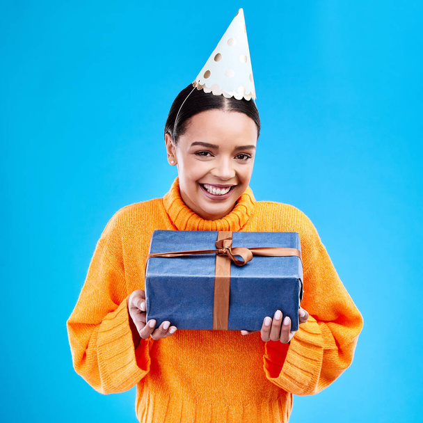 Жінка, портретна посмішка і подарунок в студії на день народження, подія або святкування на синьому фоні. Щаслива жінка посміхається і тримає подарунки або коробку для вечірки, здивує або дарує на макеті
. - Фото, зображення