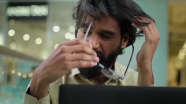 Gestresste traurige indische bärtige Mann in Brille mit Kopfschmerzen überarbeitet mit Laptop-Arbeit abnehmen Brille fühlen Augen Belastung müde erschöpft arabischer Geschäftsmann hat Geschäftsproblem verloren Job Misserfolg - Filmmaterial, Video
