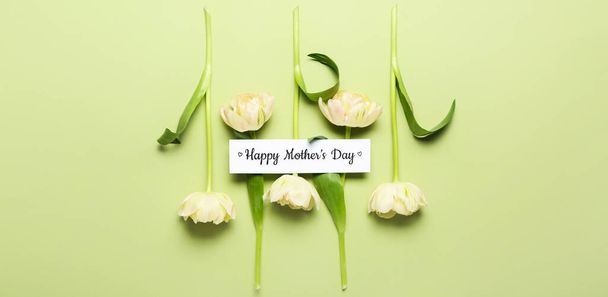 Χαρτί με κείμενο HAPPY MOTHER 'S DAY και λουλούδια σε πράσινο φόντο - Φωτογραφία, εικόνα