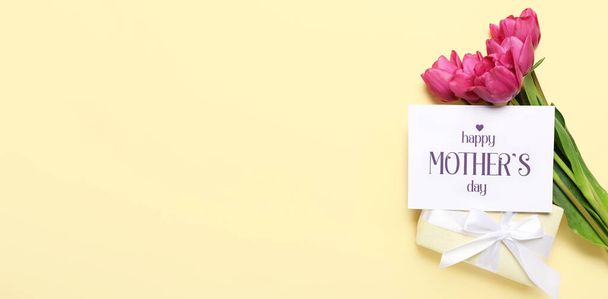 Kaart met tekst HAPPY MOTHER 'S DAY, roze tulpen en geschenkdoos op beige achtergrond met ruimte voor tekst - Foto, afbeelding