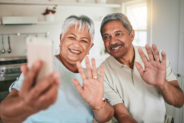 Κλήση βίντεο, χαιρετισμό και ηλικιωμένο ζευγάρι στο τηλέφωνο, χαρούμενοι και χαμογελαστοί στην κουζίνα του σπιτιού τους. Smartphone, την αγάπη και τους ηλικιωμένους χαιρετισμό, ενθουσιασμένος και χαρούμενος για online συνομιλία και απολαμβάνοντας συνταξιοδότηση. - Φωτογραφία, εικόνα