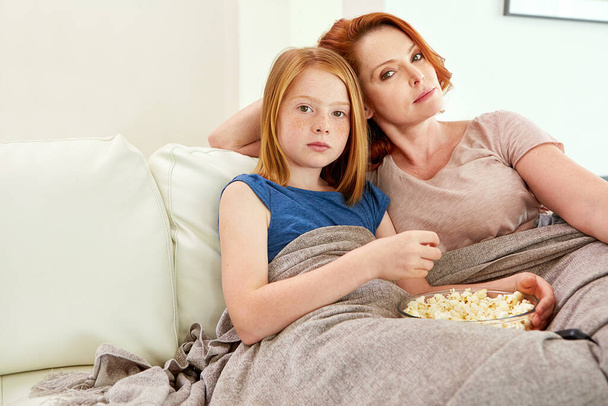 On était sérieux à propos de la soirée cinéma. une femme mûre et sa jeune fille regardant un film et mangeant du pop-corn sur le canapé - Photo, image