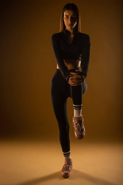 Chica en forma haciendo ejercicios de piernas en el estudio - Foto, Imagen