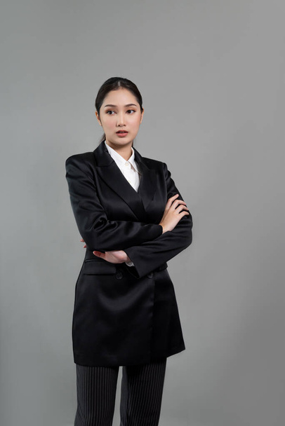 Confident young businesswoman stands on isolated background, posing in formal black suit. Office lady or manager with smart and professional appearance. Enthusiastic - Foto, imagen