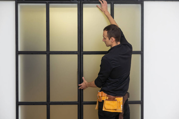 mannelijke werknemers timmerlieden installeren interieur glazen deur met een houten frame op nieuwe luxe appartement - Foto, afbeelding