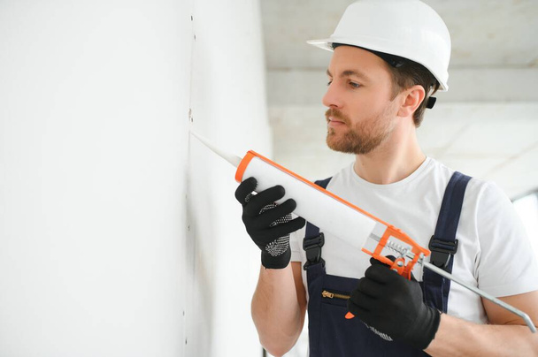 Professional Workman Applying Silicone Sealant With Caulking Gun on the Wall. - Fotó, kép