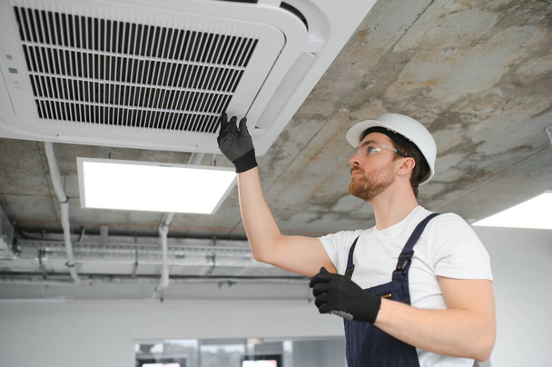 handsome young man electrician installing air conditioning in a client house - Foto, Imagen