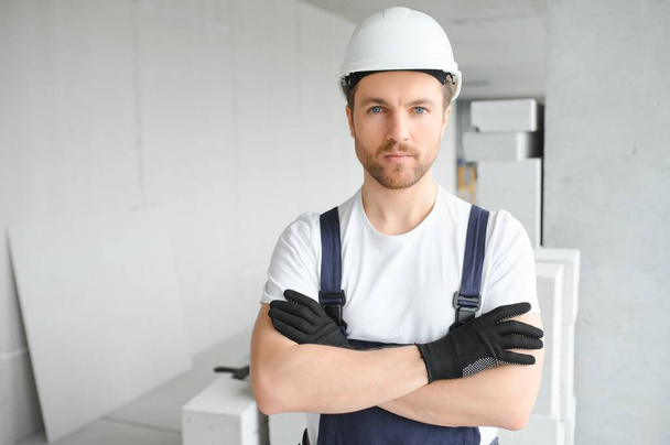 Portrait of positive, handsome young male builder in hard hat - Fotó, kép