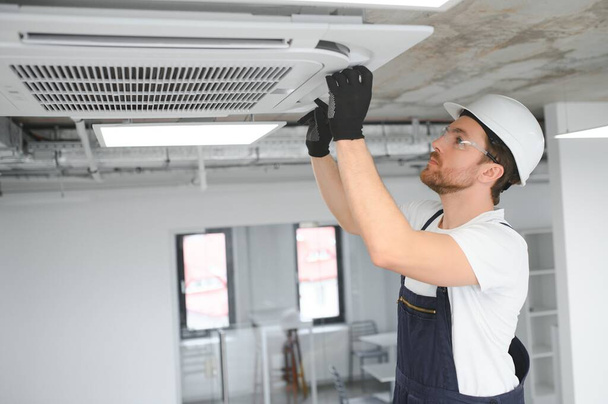 Electrician repairing air conditioner indoors. - Fotoğraf, Görsel