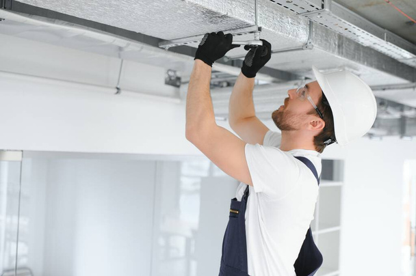 Caucasian HVAC Technician Worker in His 40s Testing Newly Installed Warehouse Ventilation System. Commercial Heating, Cooling and Air Ventilation Systems. - Foto, Imagem