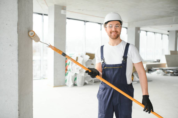 Worker renewing apartment on wall background - Foto, afbeelding