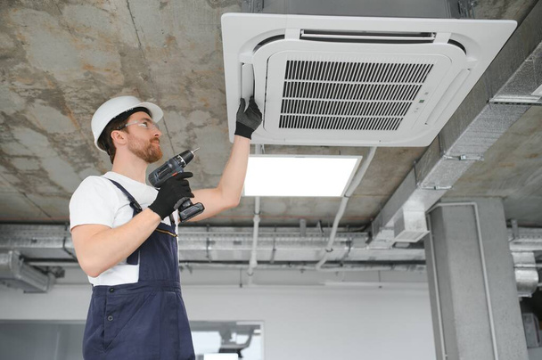 handsome young man electrician installing air conditioning in a client house - Foto, Bild
