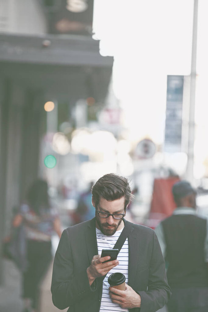 Mies kaupungilla. tyylikäs nuori mies, joka käyttää kännykkää kävellessään kaupungissa - Valokuva, kuva