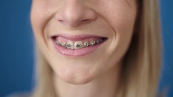 Νεαρή ξανθιά γυναίκα χαμογελά αυτοπεποίθηση δείχνει τιράντες πάνω από απομονωμένο μπλε φόντο - Πλάνα, βίντεο
